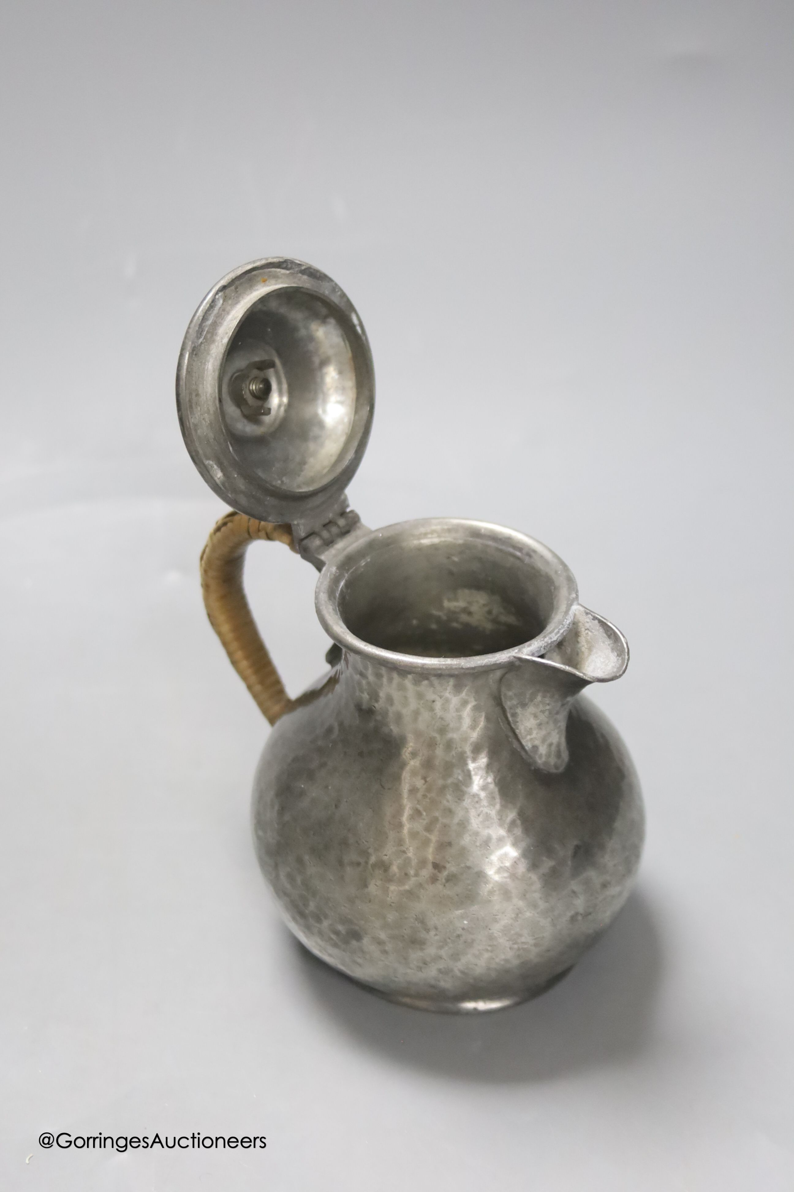 A Liberty & Co Tudric pewter pin dish, a Tudric covered jug and a pewter candleholder